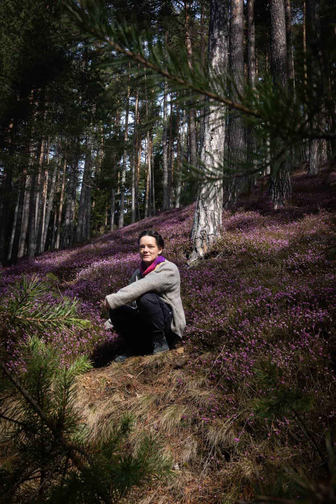 Sylvana Kuhl sitzt in blühender Heide im Wald